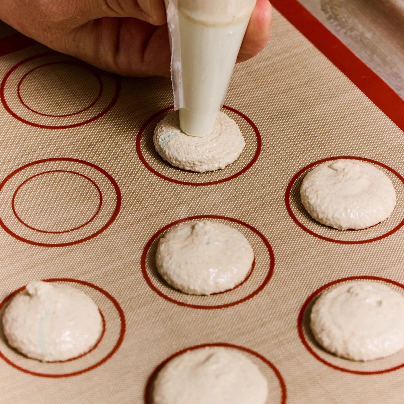 Hand piping dough onto a baking sheet with circular patterns